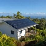 Maison tropicale équipée de panneaux solaires avec lumière ensoleillée et ambiance résidentielle sobre