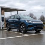 SUV électrique compact garé près d’une borne rapide sur une aire de trajet