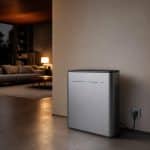 Batterie domestique compacte posée dans une pièce de vie près d’une fenêtre avec lumière naturelle