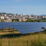 Parc solaire au sol à proximité d'une zone urbaine avec bâtiments visibles