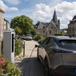 Petite place de village française avec une borne de recharge utilisée par une voiture électrique