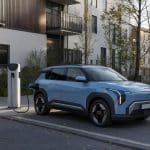 Petit SUV électrique garé en ville devant une borne de recharge domestique