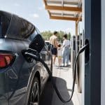 Voiture électrique branchée sur une borne rapide d'autoroute pendant un départ en vacances