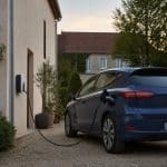 Voiture électrique d'occasion garée devant une maison avec borne de recharge
