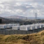 Grand site de batteries industrielles près d’infrastructures électriques sous un ciel écossais
