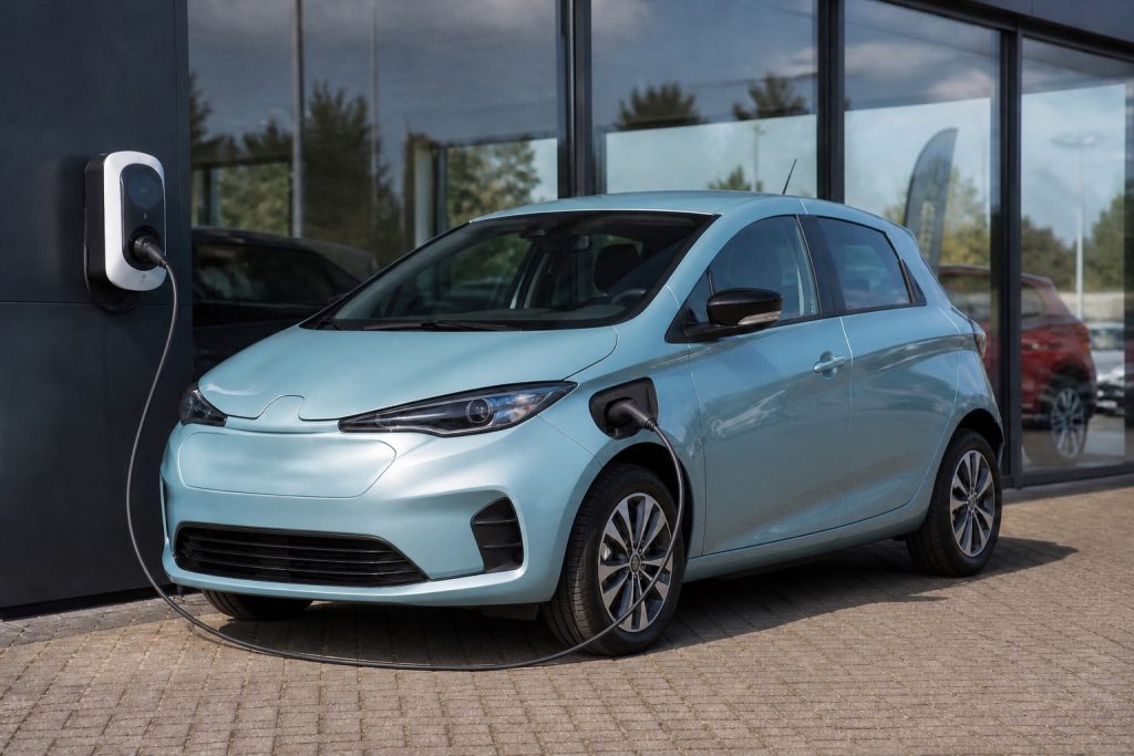 Voiture électrique d’occasion stationnée devant un garage professionnel avec borne de recharge