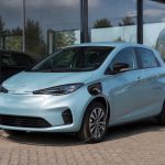 Voiture électrique d’occasion stationnée devant un garage professionnel avec borne de recharge