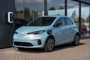 Voiture électrique d’occasion stationnée devant un garage professionnel avec borne de recharge