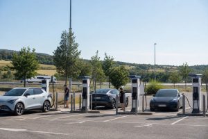 Station de recharge rapide fréquentée sur une aire française pendant les vacances d’été