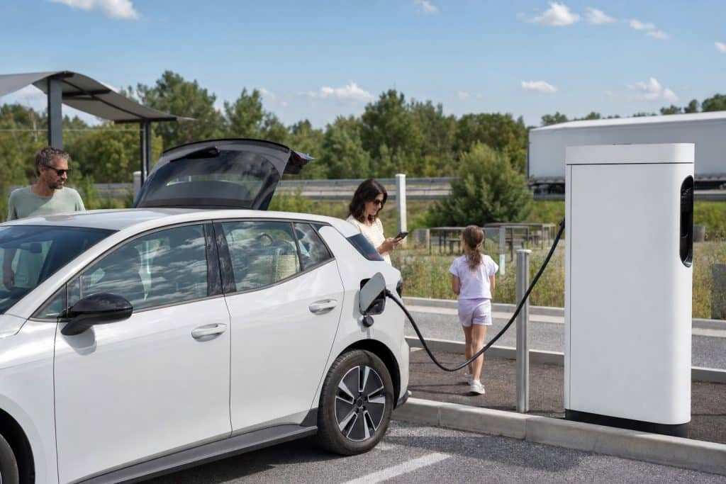 Voiture électrique en pause recharge sur une aire moderne pendant un long trajet autoroutier