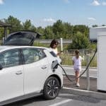 Voiture électrique en pause recharge sur une aire moderne pendant un long trajet autoroutier
