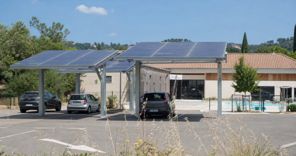 Parking équipé d’ombrières photovoltaïques devant un bâtiment public en été