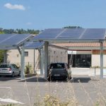 Parking équipé d’ombrières photovoltaïques devant un bâtiment public en été