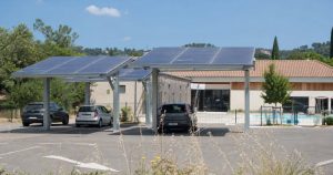 Parking équipé d’ombrières photovoltaïques devant un bâtiment public en été
