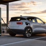 Voiture électrique en charge sur une station rapide moderne au coucher du soleil