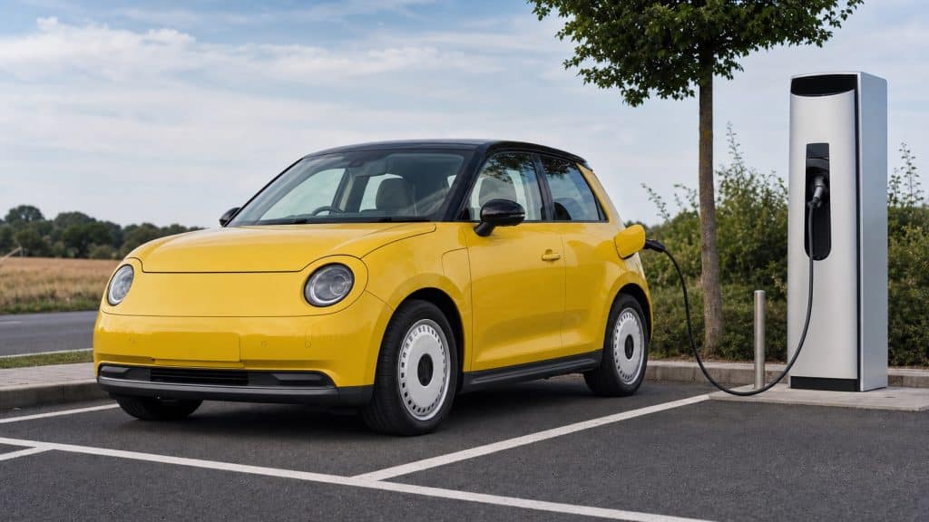 Citadine électrique jaune garée près d'une borne de recharge rapide
