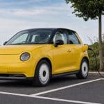Citadine électrique jaune garée près d'une borne de recharge rapide