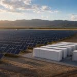 Champ de panneaux solaires avec batteries de stockage à proximité en fin d’après-midi