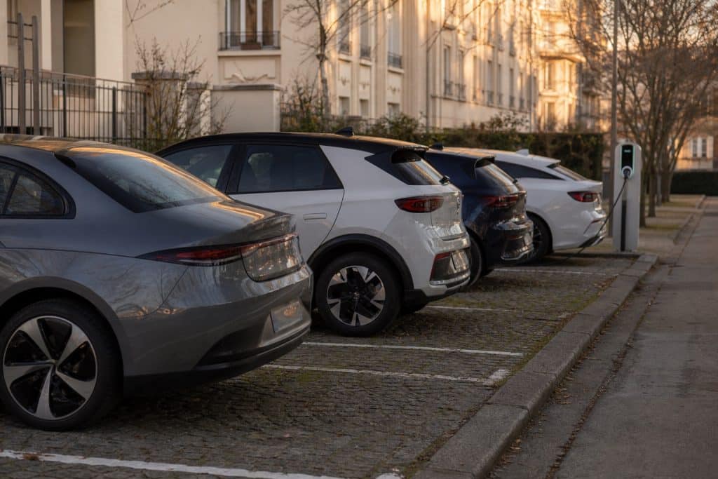 Voitures électriques récentes stationnées en ville avec borne de recharge en arrière-plan