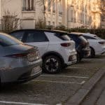 Voitures électriques récentes stationnées en ville avec borne de recharge en arrière-plan