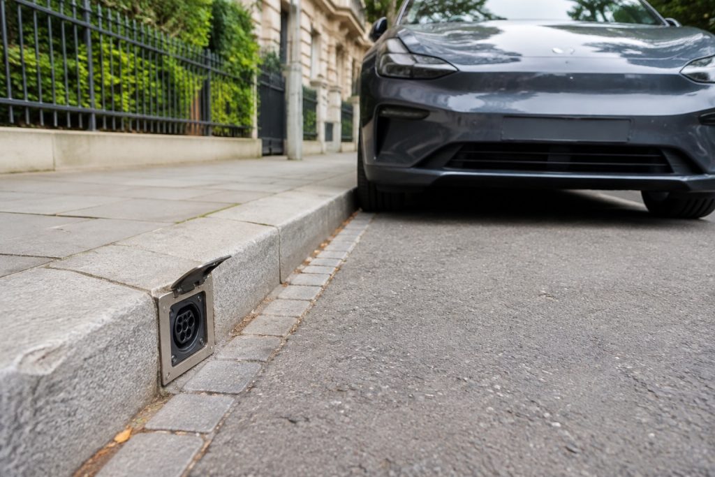 Point de recharge intégré dans une bordure de trottoir près d'une voiture électrique