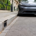 Point de recharge intégré dans une bordure de trottoir près d'une voiture électrique