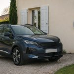 Voiture hybride rechargeable garée devant une maison près d'une borne inutilisée