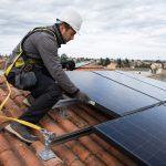 Installateur vérifiant la référence de panneaux solaires sur le toit d'une maison