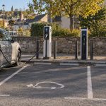 Plusieurs points de recharge publics sur un parking français, avec une voiture électrique branchée