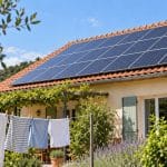 Maison française avec panneaux solaires en toiture et linge séchant au soleil, illustration de la consommation électrique en journée